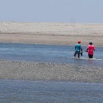 Guys wading through water during low tide on Las Penitas beach, near Leon in Nicaragua